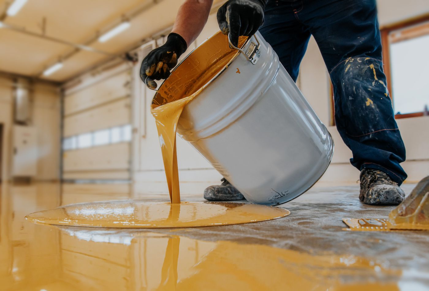 Installer pouring a fast-curing floor coating